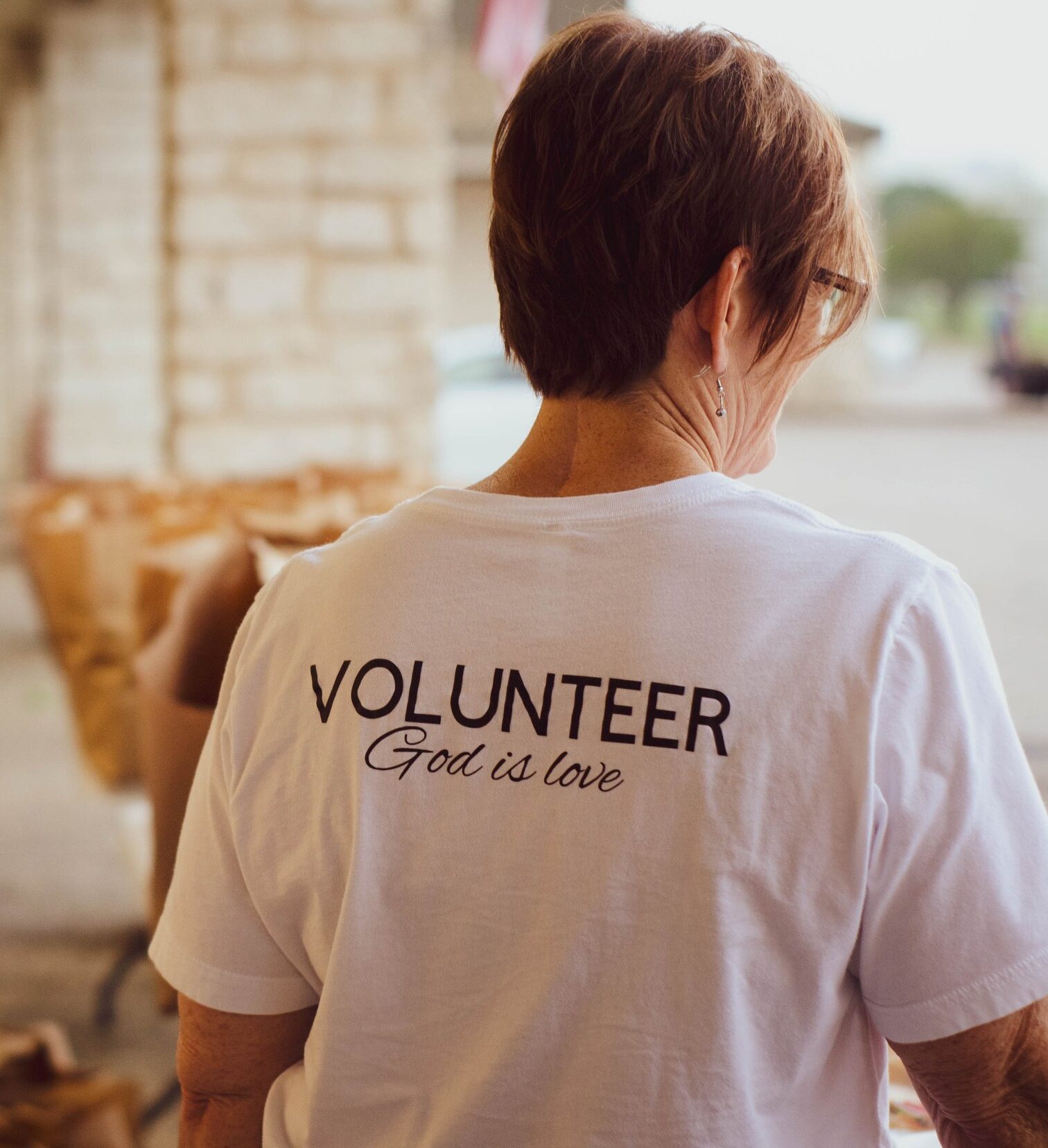 A woman wearing a white tee shirt which says volunteer.