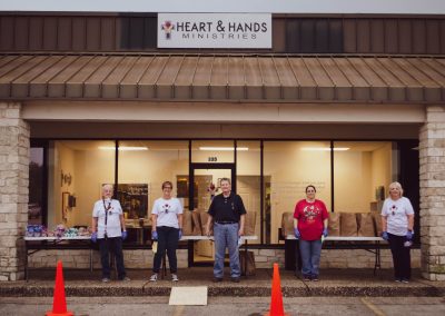 Five adults standing in front of the Heart and Hands ministries food pantry.